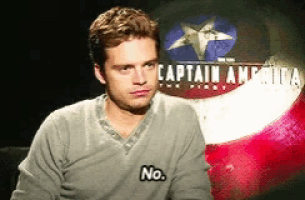 a man sitting in front of a captain america poster