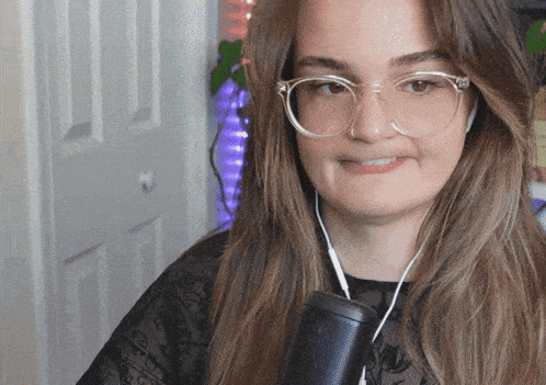 a woman wearing glasses and headphones holds a speaker