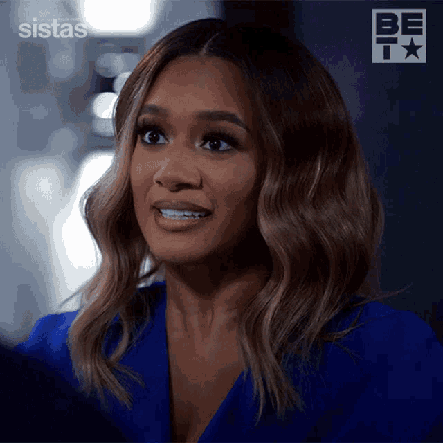 a woman in a blue jacket with the word sistas on the bottom right
