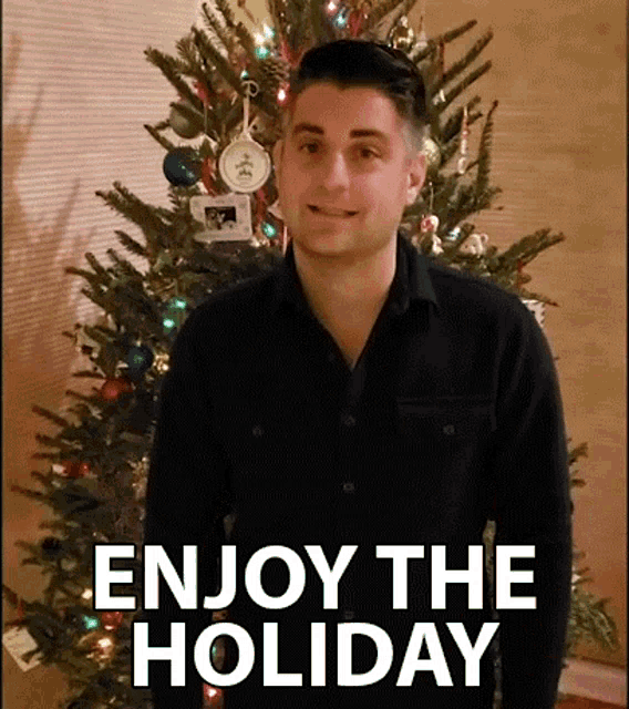 a man standing in front of a christmas tree with the words enjoy the holiday on the bottom
