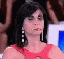 a woman wearing a red dress and earrings is sitting in front of a computer screen .