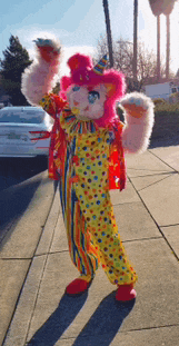 a stuffed animal dressed in a clown costume is standing on a sidewalk