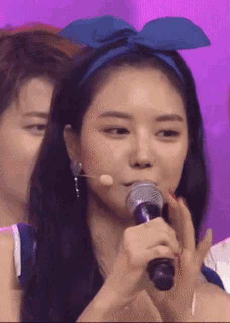 a woman wearing a blue headband holds a microphone