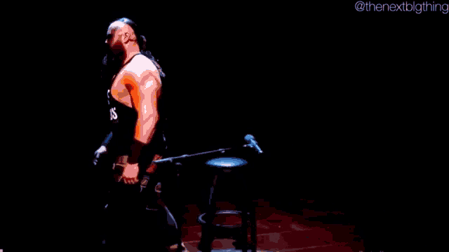 a man is playing a double bass on a stage in a dark room .