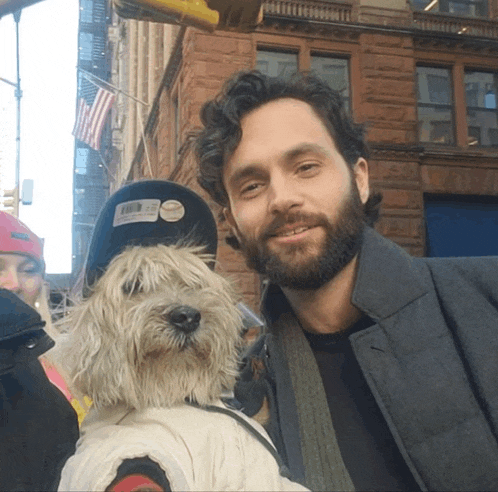 a man with a beard holds a small white dog in front of him