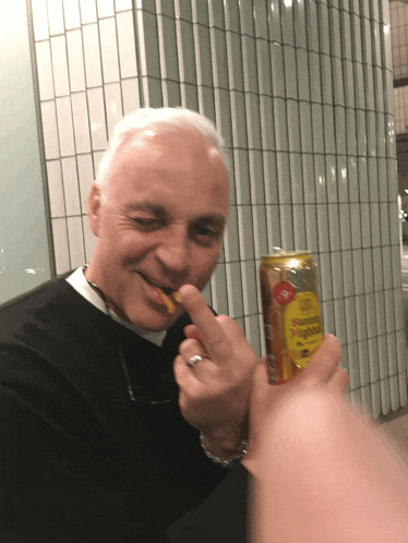 a man with a ring on his finger is holding a can that says ' ginger ale ' on it