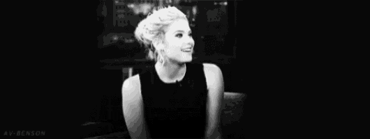 a black and white photo of a woman laughing in a chair .
