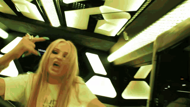 a woman with long blonde hair and blue nails is wearing a white shirt that says i 'm not okay
