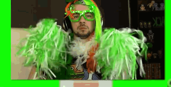 a man with green hair and feathers is sitting in front of a computer