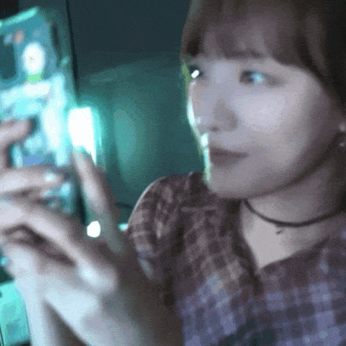 a woman in a plaid shirt is looking at her cell phone