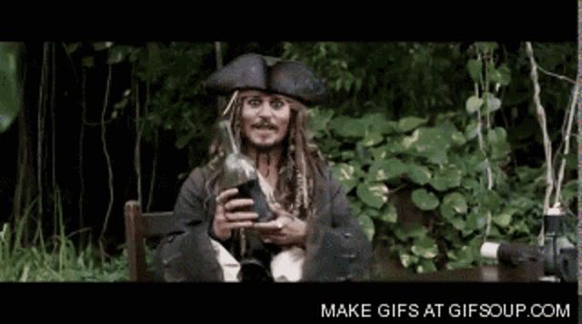 a man in a pirate costume is holding a bottle and says make gifs at gifsoup.com below him