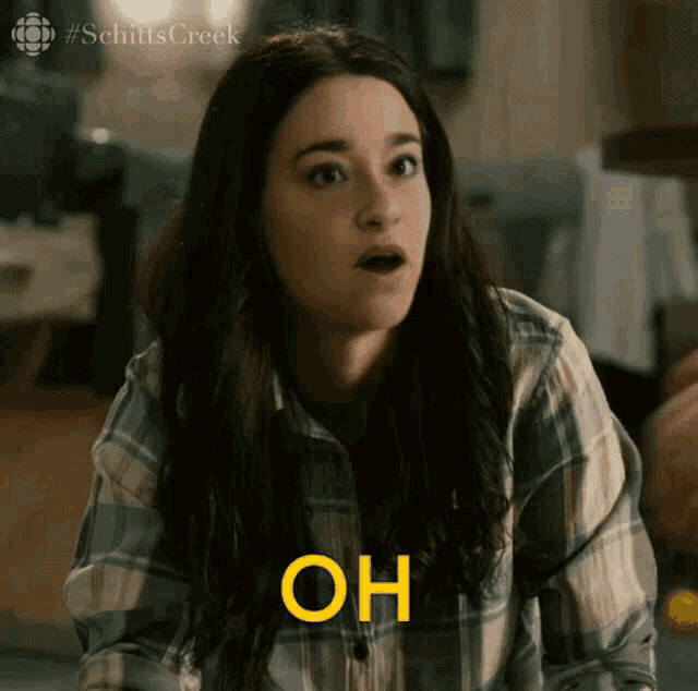 a woman in a plaid shirt is making a surprised face while holding her mouth open and saying oh .