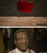 a man with glasses is smiling next to a red crown on the ground