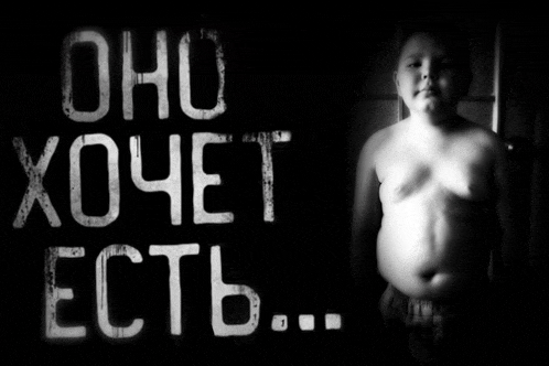 a shirtless boy stands in front of a sign that says " oho xoyet ectb "