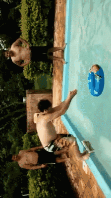 a group of men are playing in a swimming pool with a baby in a blue inner tube