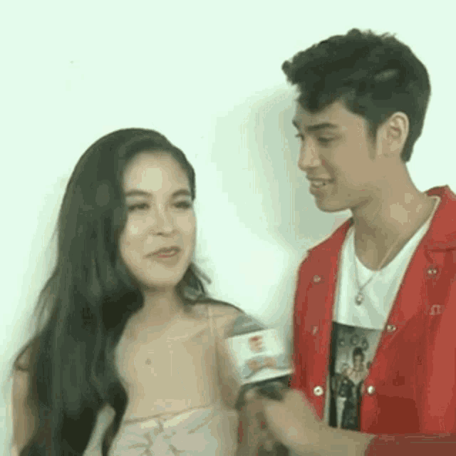 a man and a woman are talking to each other while holding a microphone .