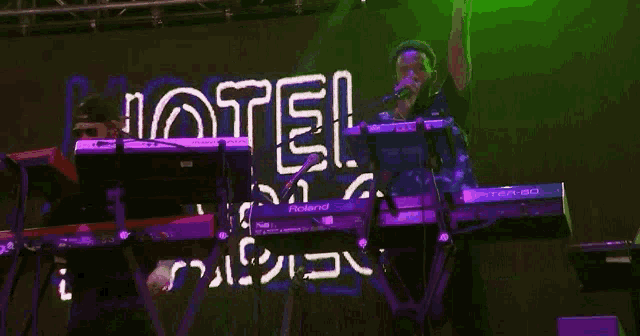 a man singing into a microphone while playing a keyboard that says roland on it