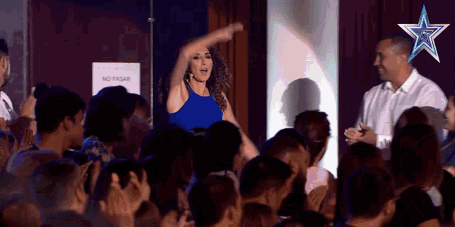 a woman in a blue dress stands in front of a crowd with a sign that says no pasar on it