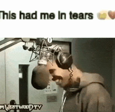 a man wearing headphones is standing in front of a microphone with the caption this had me in tears .