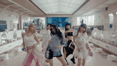 a group of girls are dancing in a bathroom with a painting on the wall behind them
