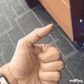 a close up of a person 's hand giving a thumbs up .