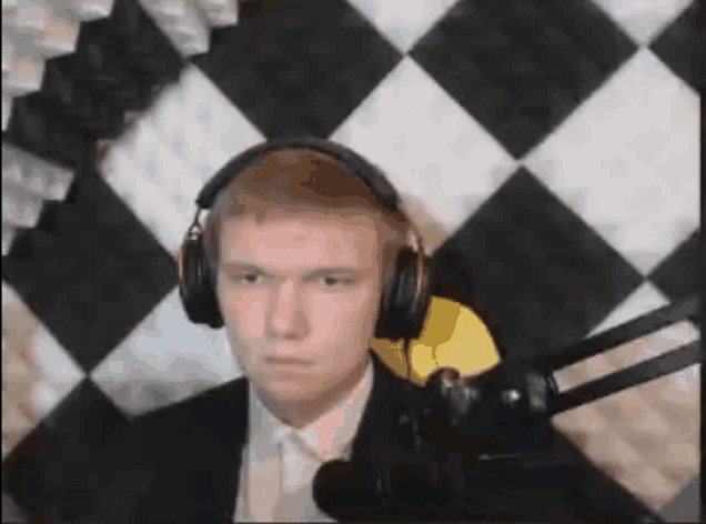 a man in a suit and tie is wearing headphones in front of a checkered wall .