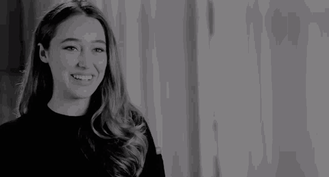 a woman is smiling in a black and white photo .