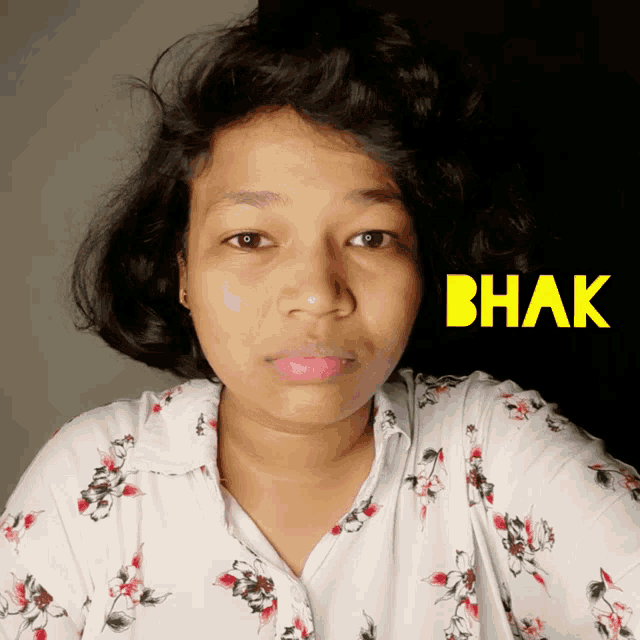 a woman wearing a floral shirt with the word mbak in yellow