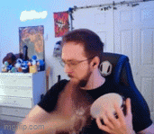 a man with glasses is sitting in a chair holding a tambourine .