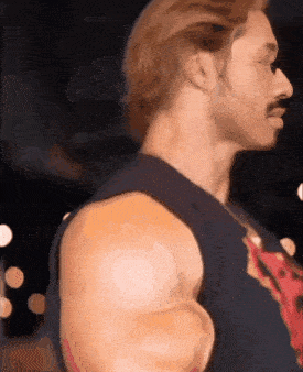 a man with a mustache and huge muscles is wearing a blue tank top