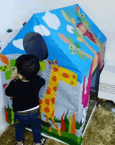 a child standing in front of a colorful playhouse