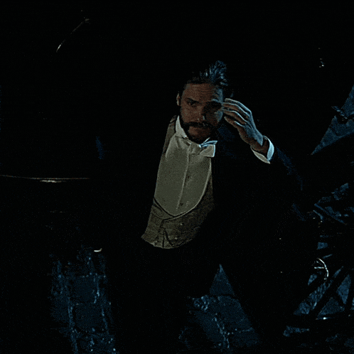a man in a tuxedo is flying through the air in a dark room