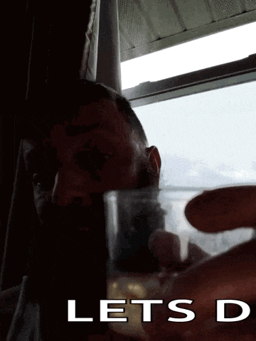 a man drinking from a plastic cup with the words " lets d " below him