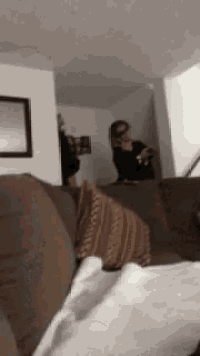 a woman is sitting on a couch in a living room looking at a mirror .