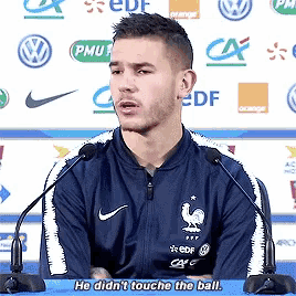 a man wearing a blue nike jacket is talking into a microphone and says he did n't touch the ball