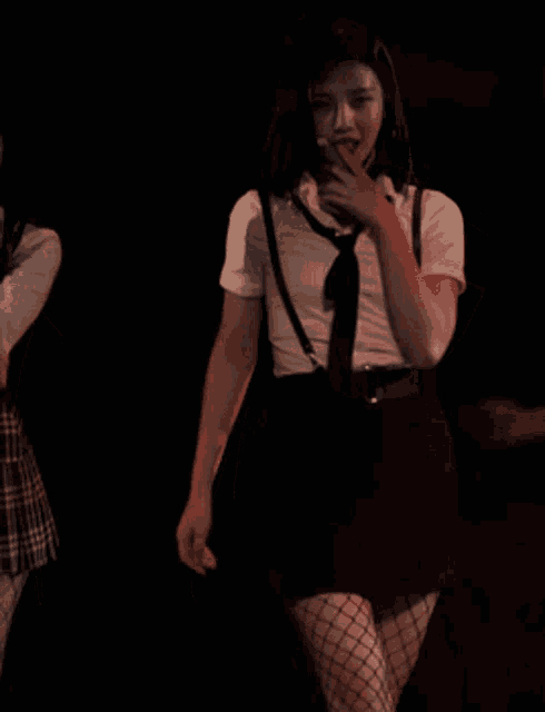 a woman wearing suspenders and fishnet stockings is dancing on a stage