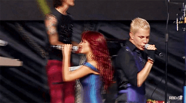 a man and a woman singing in front of a microphone with rbd.gif written on the bottom