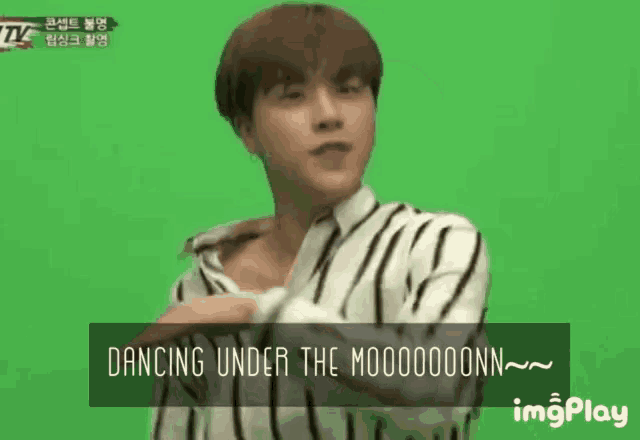 a young man in a striped shirt is dancing under the moon .