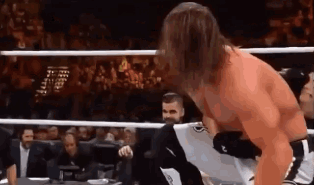 a man is wrestling another man in a ring while a referee watches .