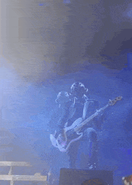 a man is playing a bass guitar on a stage in front of a crowd
