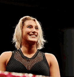 a woman in a black tank top is smiling