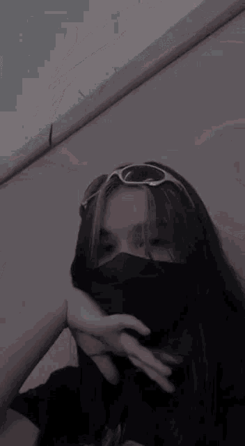 the girl is wearing sunglasses and a black mask .