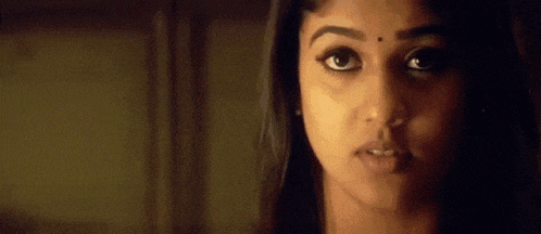 a close up of a woman 's face in a dark room with a blurred background .