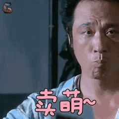 a man is making a funny face with chinese writing on his chest