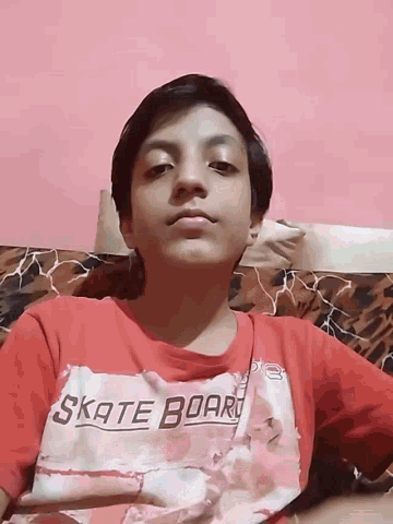 a boy wearing a red t-shirt that says skate board