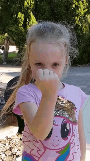 a young girl wearing a pink shirt with a pony on it
