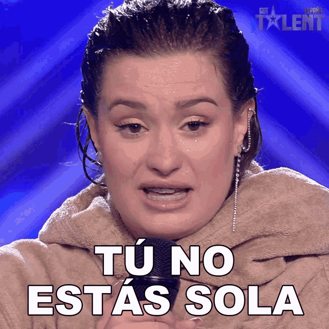 a woman with braces on her teeth holds a microphone and says " tu no estas sola " in white letters