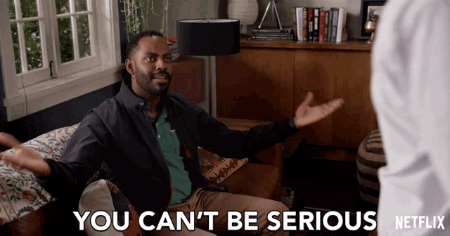 a man is sitting on a couch with his arms outstretched and says you can 't be serious