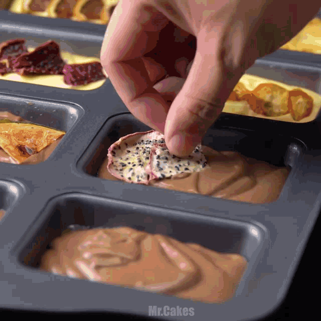 a person 's hand is reaching into a pan of food with the word mr.cakes on the bottom
