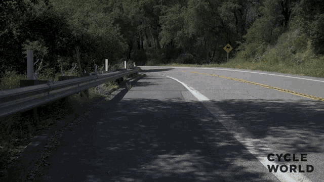 a person riding a motorcycle down a road with the words cycle world visible